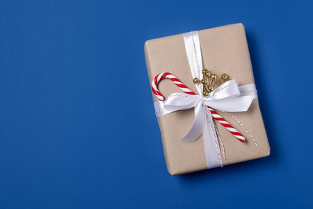 Decorated Christmas gift with candy cane on blue background, top view. Space for textの写真素材
