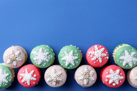 Christmas macarons decorated with snowflakes on blue background, flat lay. Space for textの写真素材