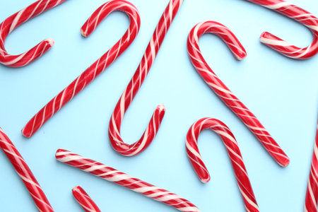 Tasty candy canes on light blue background, flat lay. Merry Christmas and Happy New Yearの写真素材