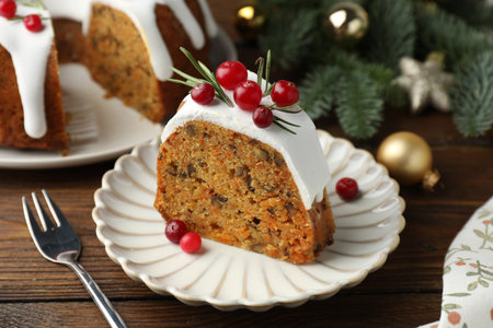 Slice of tasty Christmas cake with cranberries served on wooden table, closeupの写真素材