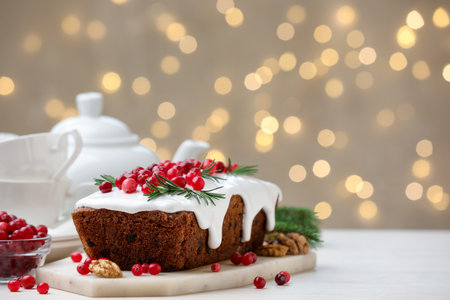 Tasty Christmas cake with red currants and rosemary on white table against bokeh lights, closeup. Space for textの写真素材