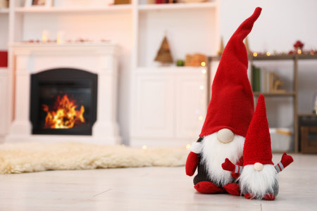 Funny Christmas gnomes on floor in decorated room, space for textの写真素材