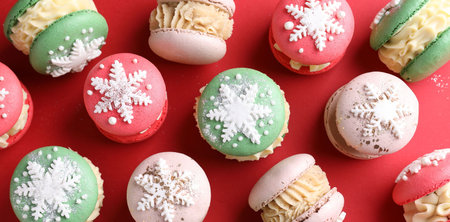 Beautifully decorated Christmas macarons on red background, flat layの写真素材