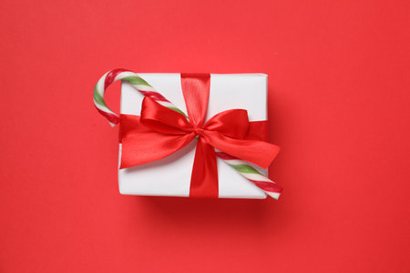 Decorated Christmas gift with candy cane on red background, top viewの写真素材