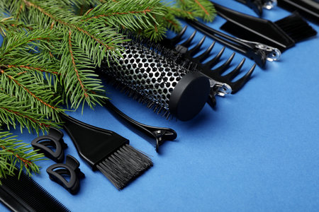 Different hairdresser's tools and Christmas tree branches on blue background, closeup. Space for textの写真素材