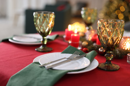 Stylish Christmas table setting with plates, glasses and burning candles in festive decorated room, closeup. Bokeh effectの写真素材