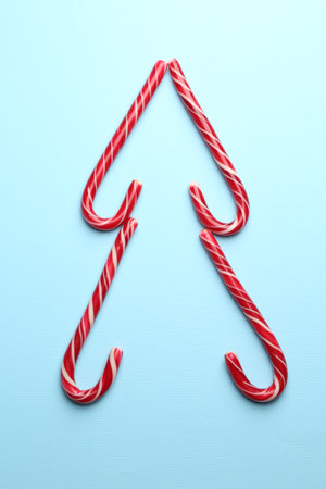 Tasty candy canes on light blue background, flat lay. Merry Christmas and Happy New Yearの写真素材