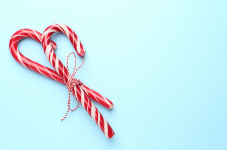 Tasty candy canes on light blue background, top view with space for text. Merry Christmas and Happy New Yearの写真素材