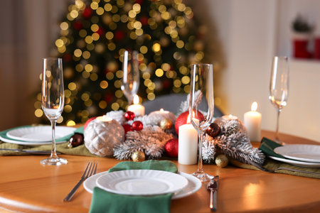Stylish Christmas table setting with plates, glasses and burning candles in festive decorated room, closeup. Bokeh effectの写真素材