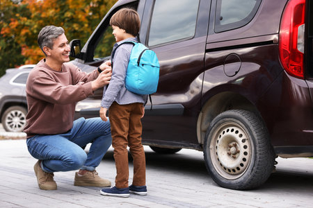 Father taking his son to school near car outdoorsの写真素材
