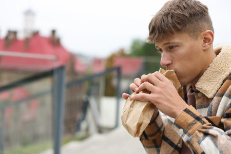 Young man with bag suffering from nausea outdoors.の写真素材