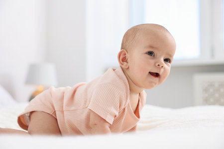 Portrait of cute little baby on bed at home