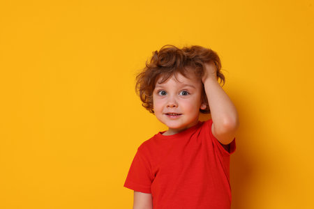 Portrait of cute little boy on orange background, space for textの写真素材