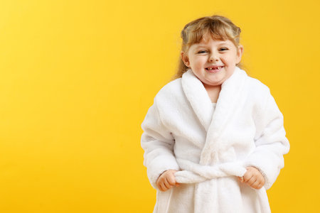Happy girl in bathrobe on yellow background.の写真素材