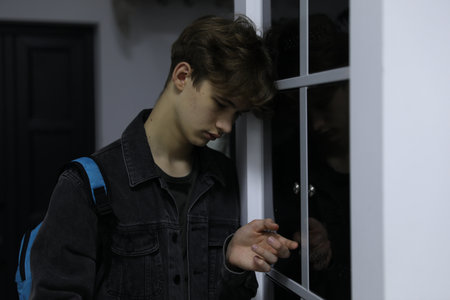 Teenage boy with backpack near lockers indoorsの写真素材