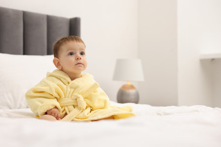 Cute baby in bathrobe on bed at home. Space for textの写真素材