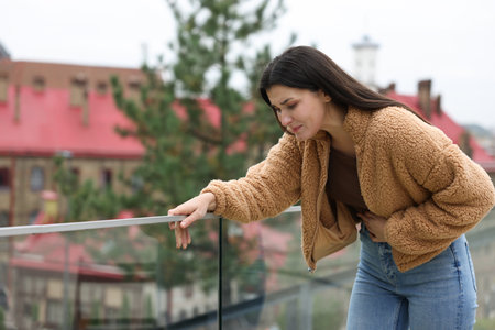 Young woman suffering from stomachache and nausea outdoors. Space for textの写真素材