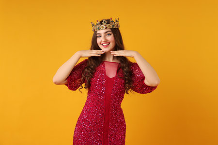 Woman wearing luxury crown on orange backgroundの写真素材