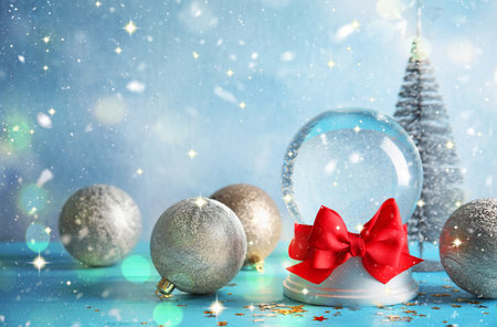 Christmas ornaments, snowglobe and fir tree on light blue background. Happy holidays