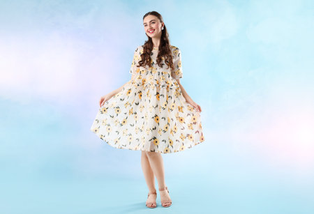Beautifully dressed young woman on light blue background