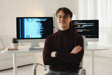 Portrait of smiling programmer with crossed arms on chair at workplace