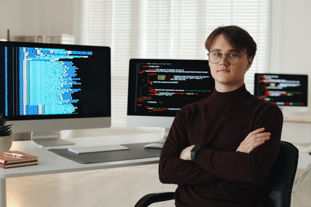 Portrait of programmer with crossed arms on chair at workplaceの写真素材