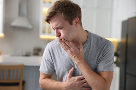 Young man suffering from nausea and stomachache indoorsの写真素材