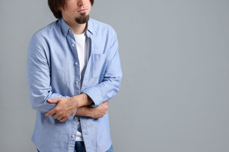 Man suffering from stomach ache and nausea on gray background, closeup. Space for textの写真素材