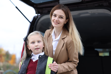 Mother taking her daughter to school near car outdoorsの写真素材