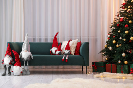 Funny Christmas gnomes on sofa in decorated roomの写真素材