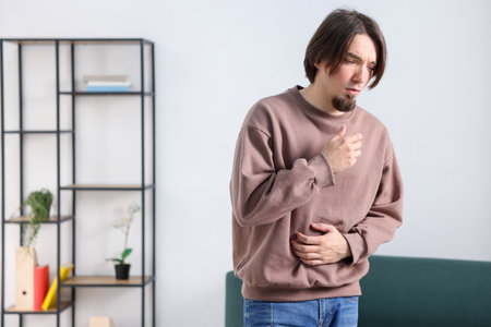 Man suffering from stomach ache and nausea at home. Space for textの写真素材