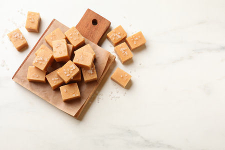 Tasty caramel candies with salt on light marble table, flat lay. Space for textの写真素材
