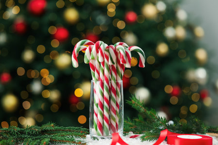 Many candy canes in glass on artificial snow against blurred Christmas lights. Bokeh effectの写真素材