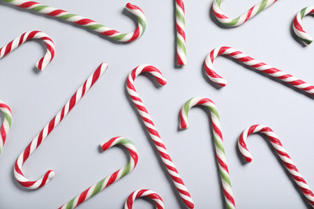Tasty candy canes on gray background, flat lay. Christmas treat