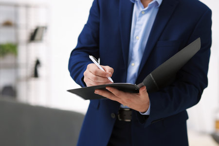 Real estate appraisal. Inspector with folder conducting property valuation at home, closeupの写真素材