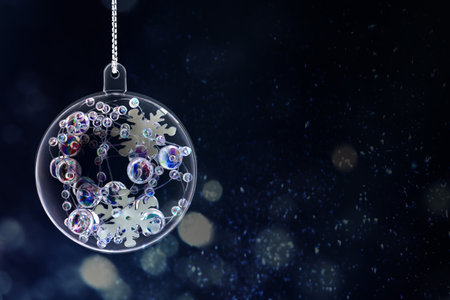 Christmas ball with snowflake and beads inside against dark backgroundの写真素材