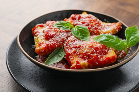 Delicious ravioli with tomato sauce, cheese and basil on wooden table, closeupの写真素材