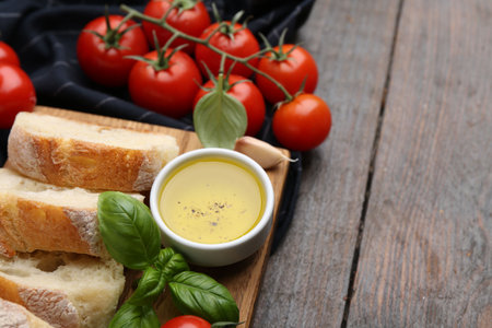 Tasty baguette served with butter, tomatoes and basil on wooden table, closeup. Space for textの写真素材