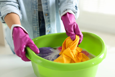 Woman washing clothes in plastic basin at white table indoors, closeupの写真素材