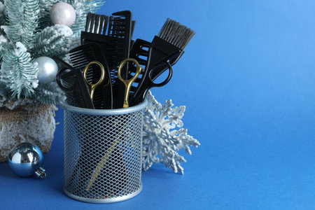 Different hairdresser's tools and Christmas decor on blue background, closeup. Space for textの写真素材