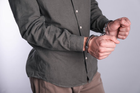 Man in handcuffs on light gray background, closeupの写真素材