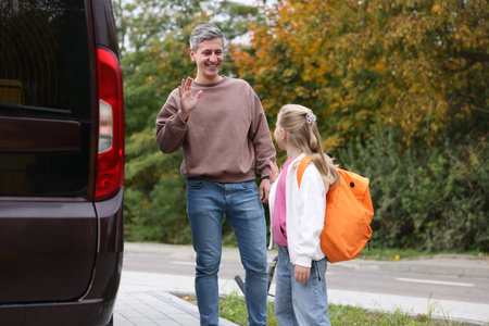 Father taking his daughter to school near car outdoorsの写真素材