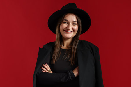 Beautiful young woman in stylish clothes posing on red backgroundの写真素材