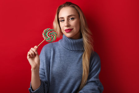 Christmas celebration. Woman with lollipop on red backgroundの写真素材