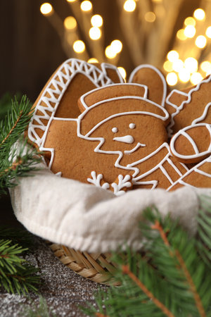 Christmas treat. Tasty gingerbread cookies in basket and decor on table, closeup. Bokeh effectの写真素材