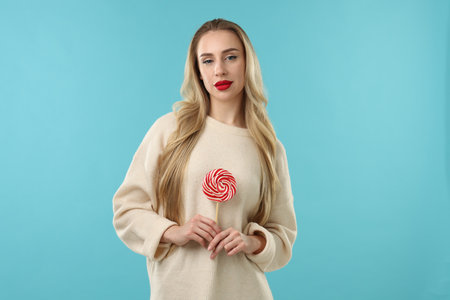 Christmas celebration. Woman with lollipop on light blue backgroundの写真素材