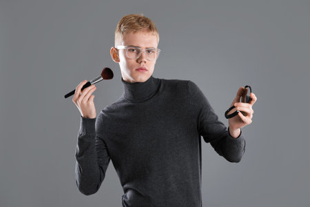 Makeup artist with powder and brush on gray backgroundの写真素材