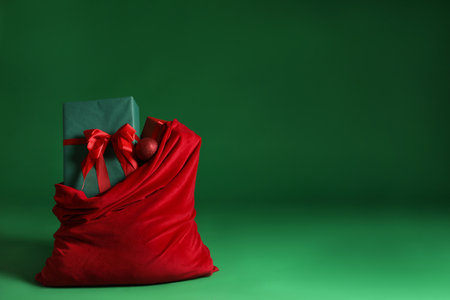 Santa Claus bag with Christmas gifts and bauble on green background. Space for textの写真素材
