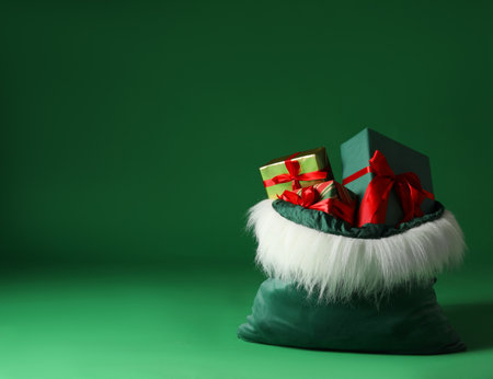 Santa Claus bag with Christmas gifts on green background. Space for textの写真素材