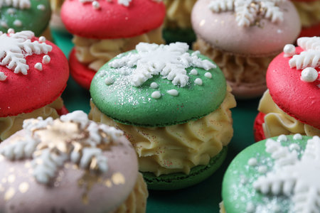 Festively decorated macarons on green background, closeup. Christmas treatの写真素材